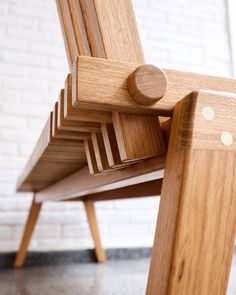 a wooden chair sitting on top of a floor next to a white brick wall in a room