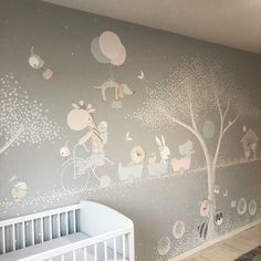 a baby's room painted in grey and white with trees, animals and balloons