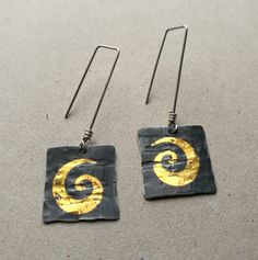 Big Golden swirls on hammered silver squares These Keum boo earrings are my absolute favorites!  Even though I do not like stencils (and the swirl is cut by one) I so like that gold swirl on the almost black silver.  Those drops were square, but hammering affected their shape, so now they are a little bit distressed - just the way I wanted them!  Silver is argentium (935) meaning ear wires should not tarnish as much as sterling silver would.  Keum boo is an ancient technique of applying golden f Keum Boo Earrings, Boo Earrings, Keum Boo Jewelry, Raw Amethyst Ring, Keum Boo, Earrings Golden, Asymmetrical Earrings, Swirl Earrings, Eye Earrings