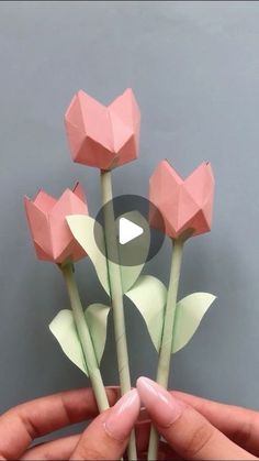 someone is holding some paper flowers in their hand and making them look like tulips