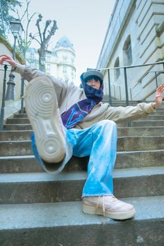 a man sitting on the steps with his foot in the air and wearing a mask