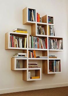 a bookshelf filled with lots of books next to a white wall