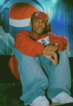 a young man sitting on top of a skateboard in front of a large screen