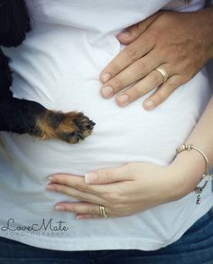 a woman holding her dog while she holds the belly of another person's stomach