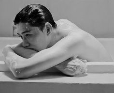 black and white photograph of a man laying in a bathtub with his arms crossed