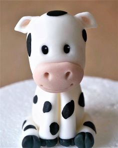 a small cow figurine sitting on top of a white cake covered in frosting