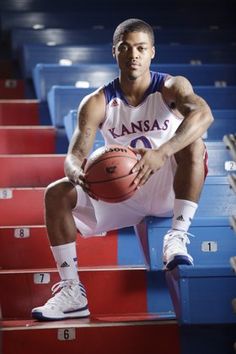 a basketball player sitting on the bleachers holding a ball