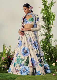 Celebrate summer with this pastel floral lehenga, featuring crystal highlights and beadwork at the waistband. The skirt's blooming print adds vibrant character, while the blouse with a sweetheart neckline and full sleeves completes the look. Includes a matching dupatta. Bohemian Lehenga With Digital Print, Summer Festive Lehenga With Printed Motifs, Bohemian Digital Print Sets For Wedding, Anarkali Lehenga With Floral Print, Bohemian Summer Floral Choli, Summer Bohemian Floral Print Choli, White Anarkali Lehenga With Floral Print, Bohemian Floral Print Lehenga For Festive Occasions, Bohemian Floral Print Choli For Wedding