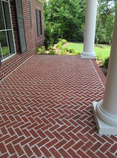 a red brick patio with white columns and windows