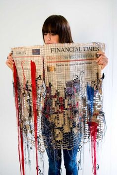 a woman is holding up a newspaper covered in strings