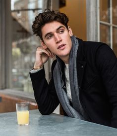 a man sitting at a table with a glass of orange juice in front of him