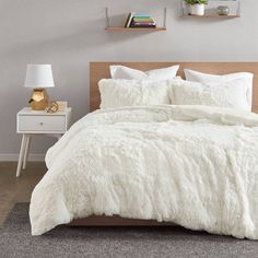 a bed with white comforter and pillows in a room