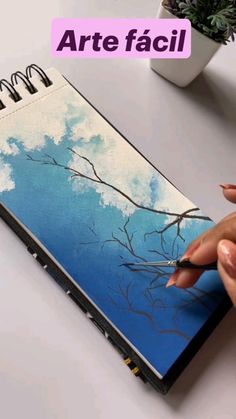 a woman is drawing on a notebook with the words art facii above it