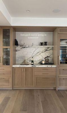 a kitchen with wooden cabinets and marble counter tops, along with wine glasses on the shelves