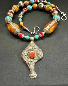 "Tibetan Nepalese handmade coral huge repousse conch vintage pendant amulet with beautiful Tibetan capped Nepalese beads unique bohemian statement necklace. This is a large chunky necklace that is bold and beautiful and guaranteed to make a statement! This necklace measures 26\" in length.  Beautiful handmade vintage beads from nepal beaded with a focal handmade Tibetan coral repousse conch amulet silver pendant.  The conch coral amulet conch is big and measures 3.5\" in height and 2\" in width. It has 20mm big red Cabochon coral in the center.   There are multiple different size and style capped silver Tibetan beads ranging in size from 14mm up to 26mm.   This piece is finished with a large Tibetan antique silver double hook clasp closure. You will get the exact pictured necklace shown on Bohemian Large Pendant Necklace From Vintage Collection, Handmade Bohemian Beads, Gems, And Cabochons For Festival, Bohemian Ceremonial Necklaces With Polished Beads, Bohemian Carved Round Beads Jewelry, Handmade Bohemian Beads Gems And Cabochons For Festival, Traditional Carved Necklaces For Festival, Handmade Bohemian Beads And Cabochons For Festival, Bohemian Carved Necklace For Festivals, Bohemian Carved Jewelry For Rituals