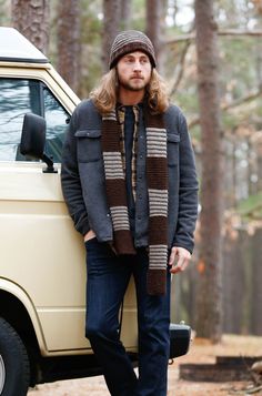 a man standing in front of a van wearing a knitted scarf and beanie