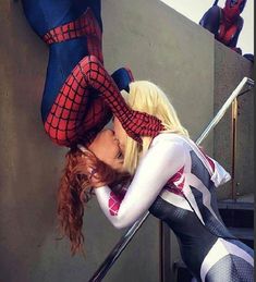 a woman dressed as spider - man kissing another woman on the cheek with her hands behind her head