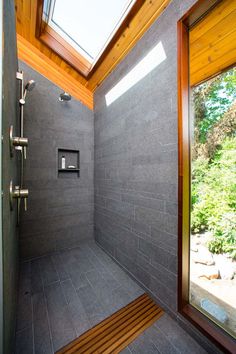 a walk in shower sitting under a skylight next to a wooden bench and window