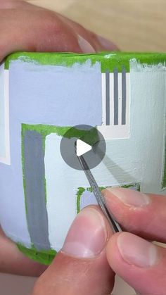 someone is painting the inside of a small object with green and white paint on it