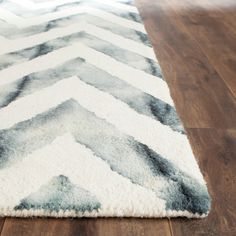 a white and gray rug on top of a wooden floor