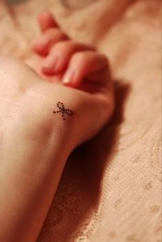 a small cross tattoo on the foot of a baby's foot, resting on a bed