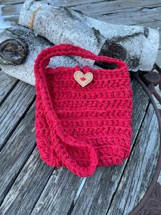 a red crocheted bag sitting on top of a wooden table next to a tree