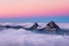 two mountain peaks above the clouds at sunset