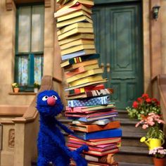 the sesame street book tower is made out of books and has a blue stuffed animal standing next to it