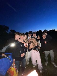 a group of young people standing next to each other at night with the moon in the background