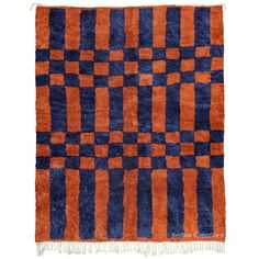 an orange and blue checkered rug with fringes on the bottom, against a white background