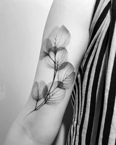 a black and white photo of a woman's arm with a leaf tattoo on it