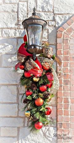 a christmas wreath hanging from the side of a brick wall next to a street light