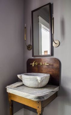 a bathroom sink sitting under a mirror on top of a wooden counter next to a wall mounted faucet