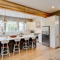 a kitchen with white cabinets and bar stools next to an island in the middle