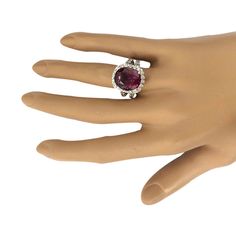 a woman's hand wearing a ring with a large oval shaped ruby stone in the center