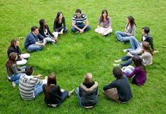 a group of people sitting in the middle of a circle on top of green grass