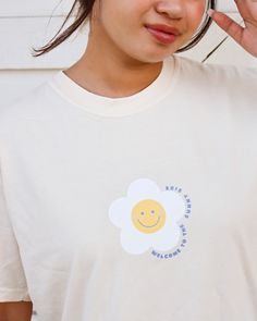 "Happy Daisy Unisex Shirt A gorgeous Ivory T-shirt with a cute smiley daisy design. This tee is unisex, soft, and durable making it perfect for any occasion. If you prefer a more cozy look, go up one size. The front design reads \"welcome to the sunny side\" with a happy daisy graphic in the middle chest area and the back of the shirt reads \"See you on the flip side\" in a gorgeous cobalt blue. This is a great T-shirt for any occasions such as birthdays, anniversaries, Christmas, etc. This desi Cute Spring Tops With Smiley Face, Cute White T-shirt With Smiley Face, Cute Smiley Face Tops For Spring, Playful Spring T-shirt For Everyday, Playful Everyday T-shirt For Spring, Cute Smiley Face Top For Spring, Cute Smiley Face Tops For Summer, Playful Smiley Face Tops For Spring, Playful White T-shirt For Everyday