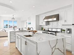 a large kitchen with white cabinets and marble counter tops, along with stainless steel appliances