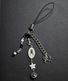 a black and white photo of a key chain with a spider charm hanging from it's side