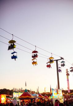 an amusement park filled with lots of people riding on top of swings and cars driving down the road