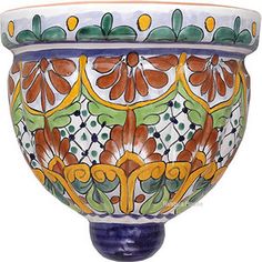 an ornately painted bowl with flowers and leaves on the outside, sits in front of a white background