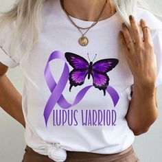 "Lupus Warrior with purple ribbon and butterfly shirt. We specialize in unique and empowering t-shirts for lupus warriors. Our Lupus Warrior Shirt features a bold design with the words \"Lupus Warrior\" and a purple ribbon, symbolizing lupus awareness. It's made from soft and comfortable unisex jersey fabric, perfect for everyday wear. With our Purple Ribbon Awareness Shirt, you can proudly show your support for lupus awareness and join the movement of wearing purple in May. Join us in spreading awareness and empowering lupus warriors with our stylish and meaningful t-shirt! CUSTOMIZE: If you see a specific design in my shop that you would rather have on a tee, sweatshirt, hoodie, youth shirt, tote bag etc. just let me know. I would be happy to make you a custom listing. This classic unise Purple Ribbon Awareness, Ribbon Awareness, Wearing Purple, Butterfly Shirt, Warriors Shirt, Butterfly Shirts, Youth Shirt, Purple Ribbon, Awareness Shirt