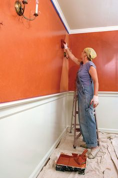 a woman is painting the walls in an orange room