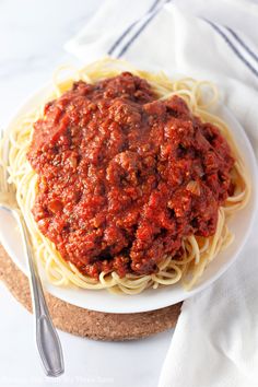 a plate of spaghetti with meat sauce on it and a fork next to the plate