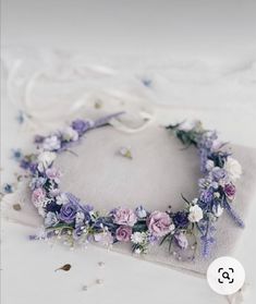 a flower crown on top of a white cloth covered pillow with purple and pink flowers