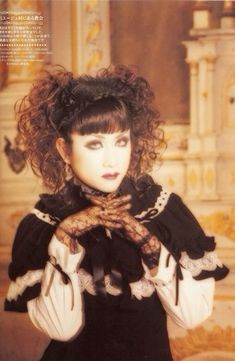 a woman with curly hair wearing a black and white dress holding her hands over her chest