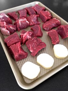 raw and uncooked meat on a baking sheet ready to be cut into cubes