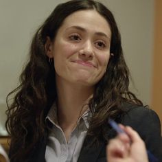 a woman sitting at a table with a pen in her hand and looking off to the side