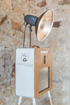 an old fashioned projector sitting on top of a wooden stand next to a stone wall