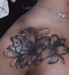 a woman's back with flowers and butterflies tattoo on her left side ribcage